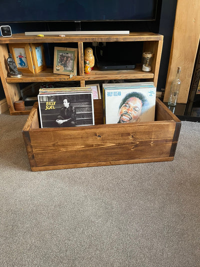 a wooden box filled with vinyl records in front of a tv