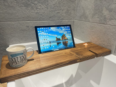 bath board holding a tablet and a glass